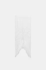 Falda midi semitransparente de punto crochet color blanco, con cintura elástica y bajo asimétrico con flecos.