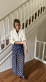 Falda larga de tiro alto color azul marino con estampado de lunares blancos, confeccionada en gasa de seda. Presenta corte ajustado en la cadera con frunces frontales y diseño fluido en la parte inferior.