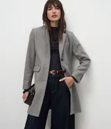 Abrigo largo de corte slim, color gris con textura jaspeada. Presenta solapas clásicas, cierre frontal con botones, bolsillos laterales con solapa y abertura trasera. Incluye forro interno.