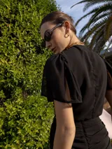 Top negro con escote en V, mangas cortas amplias y lazo central para atar.