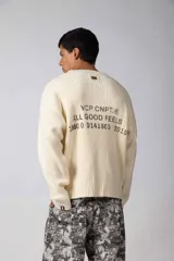 Sweater de punto acanalado con diseño de calce relajado, cuello redondo y mangas largas. Presenta una estampa gráfica pequeña en el centro del pecho y un parche con logo en el puño.