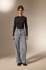 Pantalon de jean de corte recto y tiro medio, con detalle de ojales metálicos a lo largo de la costura lateral externa.