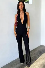 Enterizo largo de encaje negro, con escote profundo tipo halter y diseño ajustado en el torso con piernas acampanadas.