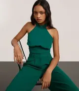 Top cropped de crepé color verde esmeralda, con escote halter y cuello alto. Presenta un canesú fruncido en la cintura que ajusta la prenda al cuerpo.