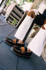 Mocasines negros con aplique de cuero color caramelo y detalle de costuras en la capellada.