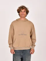 Hoodie color beige con bolsillo frontal tipo canguro, puños y ruedo acanalados. Presenta un estampado gráfico minimalista en el centro del pecho con texto en azul oscuro.