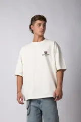 Remera oversize color crema de algodón premium, con estampado frontal de un perro con lentes de sol y el texto "Richer & Louder VCP".