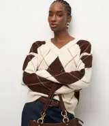 Suéter de punto con diseño de cuadros argyle en tonos marrón y crema, cuello en V y mangas largas con sisa caída.