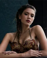 Vestido con falda plisada color dorado y top diseñado en jacquard con estampado paisley en tonos borgoña, ocre y dorado. Se ajusta al cuello con tiras de cadenas doradas.