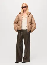 Chaqueta puffer corta color tostado con capucha, bolsillos laterales con ribete, cierre frontal con cremallera y diseño oversize acolchado.