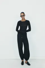 Pantalón de tiro medio con cintura elástica ajustable mediante cordones. Presenta bolsillos delanteros y bajos terminados en puño elástico con detalle de botón.