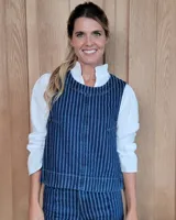 Chaleco de corte recto y largo a la cintura, confeccionado en denim con estampado de rayas verticales en tonos azul y blanco. Presenta cuello redondo y costuras visibles que definen su estructura.