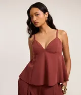 Blusa corta color terracota, con escote en V, breteles finos ajustables y detalle peplum en el dobladillo. Presenta aberturas en la espalda.