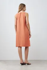 Vestido midi de lino color durazno, corte recto y sin mangas.