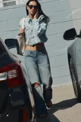 Campera de jean crop color celeste con efecto lavado, cuello solapa, mangas largas con hombreras, bolsillos con solapa en el pecho y detalles de rotos. Cuenta con cierre frontal de botones y bajo fruncido.