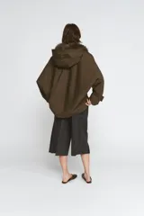 Trench corto de corte recto con capucha y cuello desmontable efecto pelo. Presenta cierre frontal con botones, bolsillos laterales y mangas largas con trabillas en los puños.
