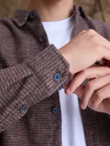Overshirt de textura tipo tweed en color marrón, con cuello clásico, cierre frontal de botones y bolsillo en el pecho.