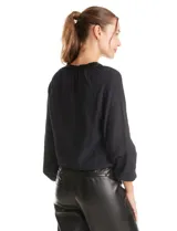 Blusa de satén color verde petróleo, con escote en V y cuello decorado con mostacillas bordadas. Presenta mangas largas con puños elásticos y ruedo también elastizado, brindando un ajuste cómodo y holgado.