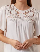 Blusa color crema de crepe con detalle de crochet en el escote, mangas cortas amplias.