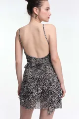 Vestido corto de tirantes finos con estampado de cebra en blanco y negro, escote en V y espalda baja. Presenta volados y frunces que realzan la figura.