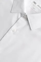 Camisa slim fit blanca de manga larga, cuello italiano y puños con botón. Cierre frontal de botonadura.