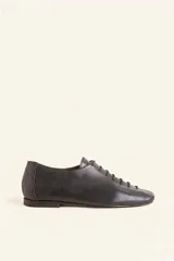 Zapato chato de cuero negro con cordones finos y punta redonda.