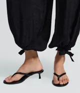 Pantalón estilo aladino color bordó, confeccionado en tejido crepé con textura. Presenta cintura elástica, corte holgado en las piernas y ruedo ajustado con lazo decorativo.