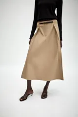Falda midi de tiro alto en color beige, con diseño evasé y pliegues laterales. Incluye un cinturón fino a contraste en color negro con hebilla metálica y cierre frontal con cremallera y gancho.
