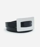 Cinturón de poliuretano color negro con textura suave, presenta una hebilla rectangular grande de metal plateado con acabado brillante.