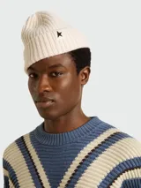 Gorro tipo beanie de lana en color crema, con tejido acanalado y parche con estrella negra en el frente.