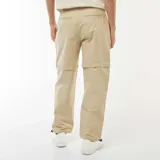 Pantalón de gabardina color beige, con diseño convertible 2 en 1 que permite desmontar la parte inferior para transformarlo en short. Presenta corte recto, bolsillos laterales y ajuste en los tobillos con cordón elástico.