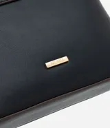 Bolsa bandolera de estructura firme en color marrón oscuro, con cierre de cremallera metálica y correa larga ajustable con hebilla.