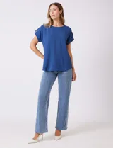 Blusa de crepe color blanco, con cuello redondo a la base y mangas cortas con detalle de presilla y botón en el borde.