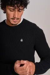 Sweater de punto con textura acanalada, color negro, de cuello redondo y manga larga. Presenta un pequeño logo bordado en el pecho.