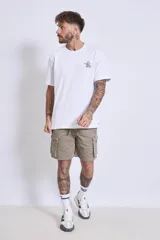 Remera blanca de algodón, corte holgado, con cuello redondo y un pequeño logo bordado en azul claro en el pecho.