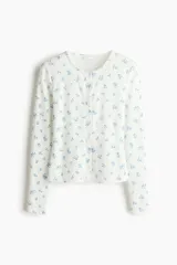 Cardigan ajustado de punto pointelle en color blanco, con pequeño estampado floral azul, escote redondo y cierre frontal de botones con ribetes de picot.