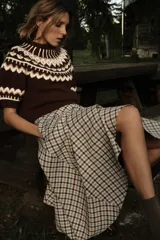 Jersey de punto color marrón con cuello redondo y manga corta abullonada. Presenta un diseño jacquard combinado en tonos beige, blanco y marrón en el canesú y los puños.