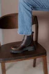 Botas tipo Chelsea de cuero con acabado vintage, diseño de caña media con paneles elásticos laterales y suela track robusta.