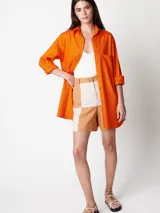 Short de lino color beige y naranja, de tiro alto con elástico en la pretina trasera, cierre delantero y botón, bolsillos delanteros y dobladillo invisible.