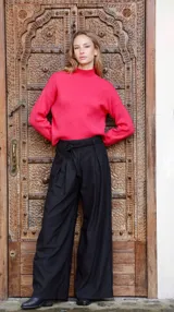 Pantalón negro de corte amplio con finas rayas verticales plateadas, pinzas frontales, elástico y lazo en la cintura.