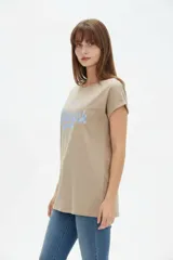 Remera de algodón color beige, de manga corta con vuelta, cuello redondo y corte holgado. Cuenta con un estampado frontal con la inscripción "Manhattan New York East Coast" en tonos celestes.