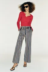 Pantalón de tiro alto y pernera recta con estampado de rayas verticales en tonos azul, marrón y beige. Incluye un cinturón delgado de color marrón oscuro con hebilla metálica dorada.
