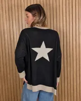 Buzo largo tejido de punto color negro, con diseño oversize, manga larga y gran estrella contrastante en la espalda. Presenta ribetes en tono beige en el cuello, los puños y el ruedo.