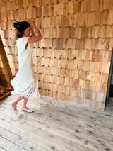 Vestido tejido color blanco con hilo metalizado, corte oversized, mangas cortas y flecos en el ruedo.