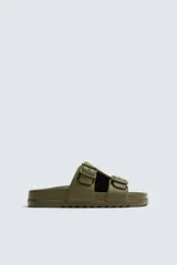 Sandalia tipo slide de goma, color verde militar, con dos tiras anchas ajustables mediante hebillas cuadradas. Presenta plantilla anatómica y suela gruesa con relieve.