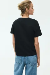 Remera de corte recto y suave tejido de algodón, color negro, con cuello redondo ribeteado y mangas cortas con hombros ligeramente caídos.