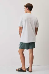 Remera blanca de manga corta y corte holgado, con cuello redondo y pequeño estampado en el pecho.