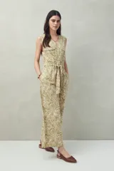 Mono largo sin mangas de algodón con estampado de hojas en tonos verde y beige. Tiene cuello en V, cierre frontal con botones, bolsillos laterales y cinturón de lazo.
