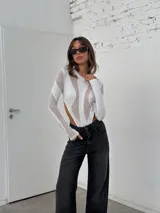 Body blanco de mangas largas con transparencias y recortes geométricos.