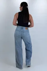 Pantalón wide leg de denim celeste claro, con costuras deflecadas y detalles deshilachados en la cintura y el remate de las piernas.